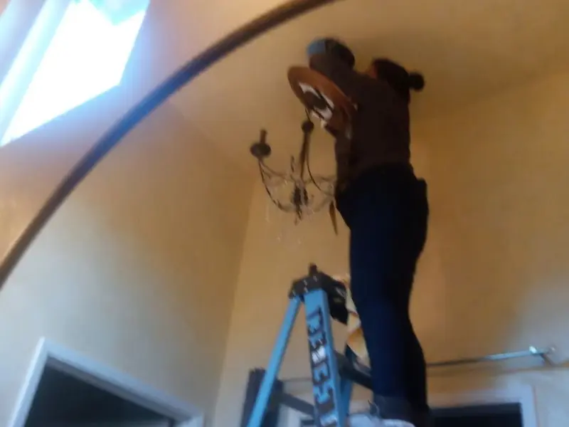 Electrician installing a chandelier in a Manhattan residence